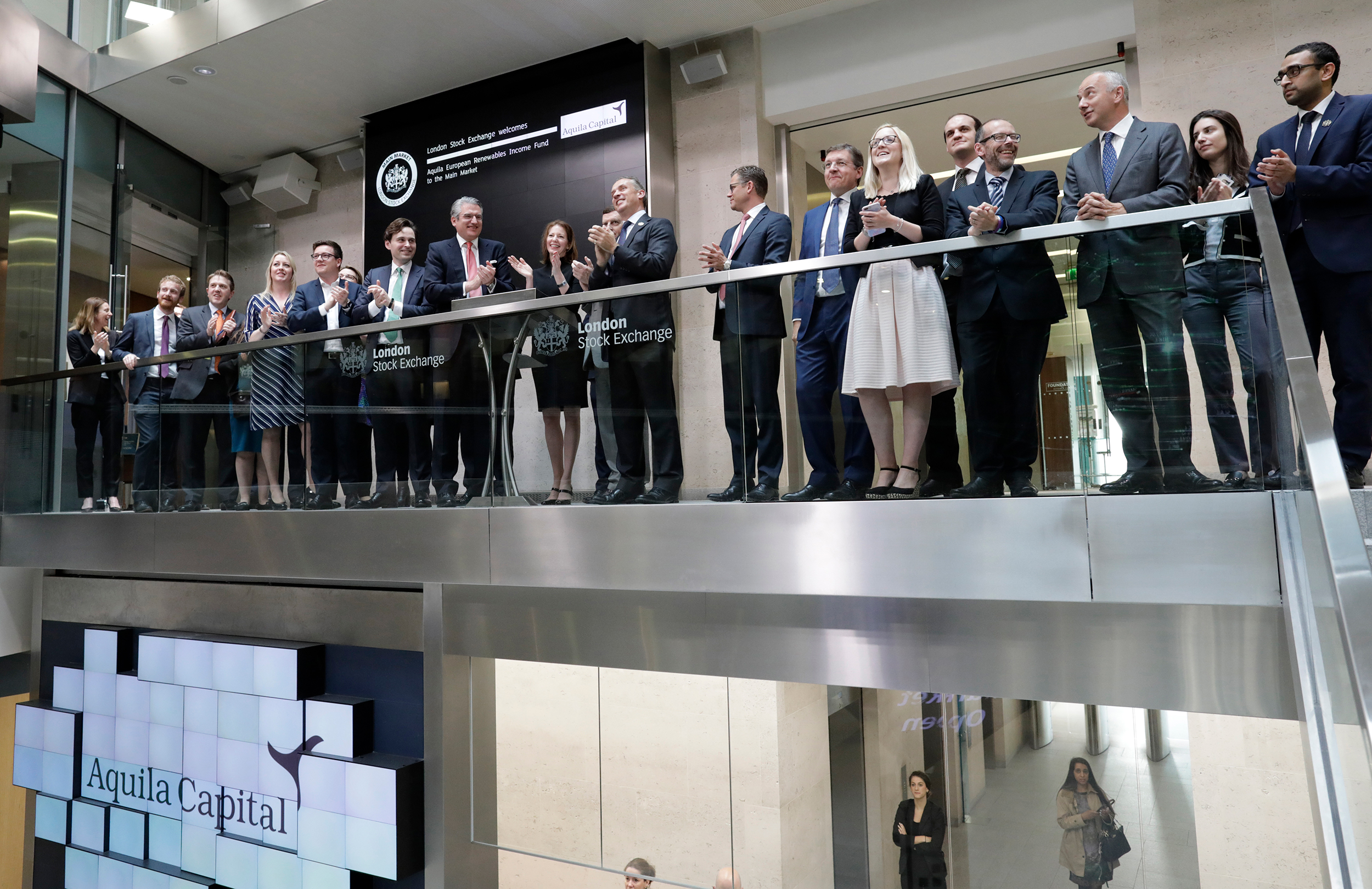 A large group of professionals clapping on a balcony at Aquila Capital