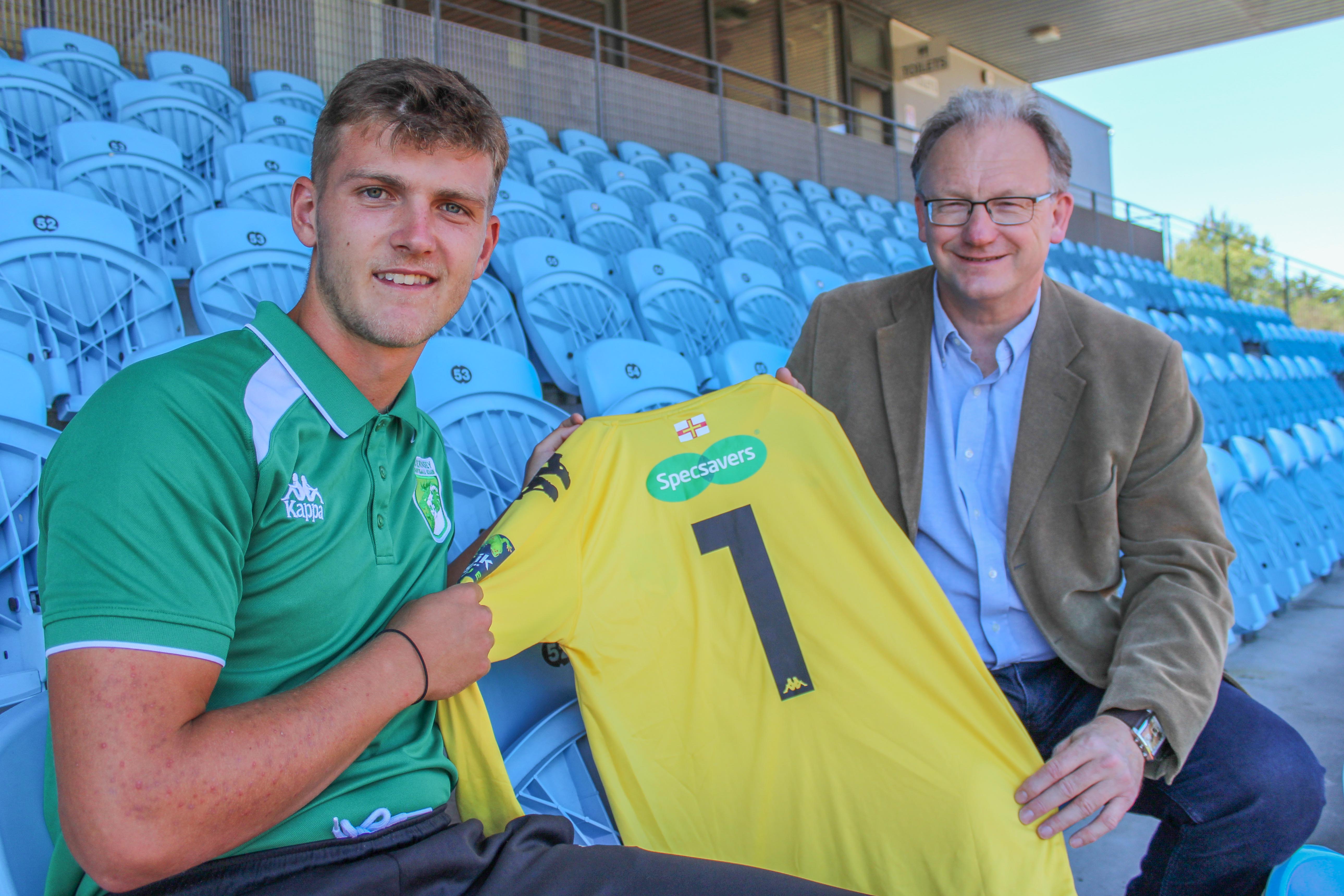 Robin Smith sitting with a member of the GFC holding up an item of their new kit
