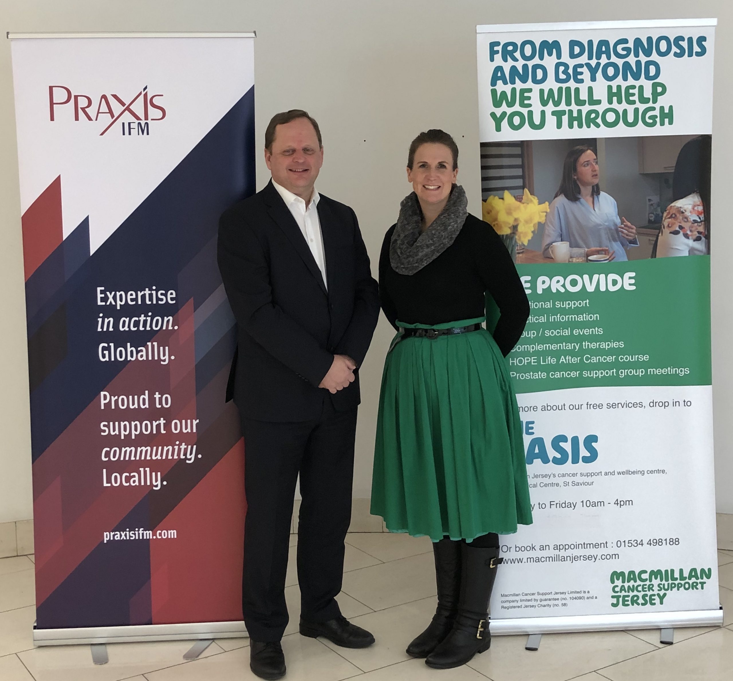Richard Kearsey standing with a lady in front of Praxis IFM and Macmillan pop up banners